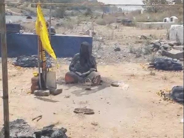 कंडों के बीच बैठी महिला।